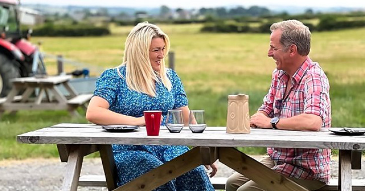 Robson Green and Sara Davies sat on bench talking at Teesdale Cheesemakers © BBC